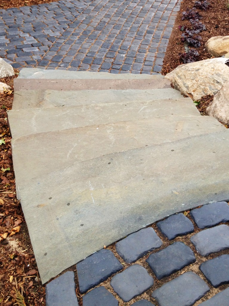 multi colored stone slab stairway between dark gray pavers