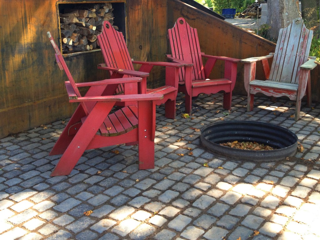 three red adirondack chairs around a fire pit