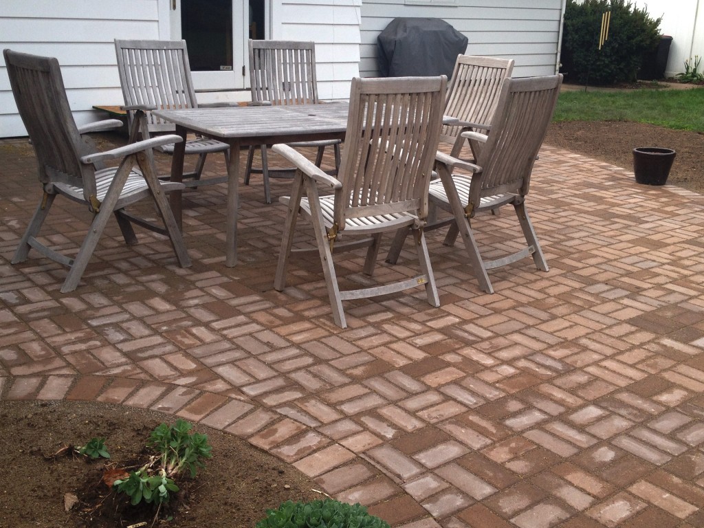 wet brick patio with wooden table and chairs