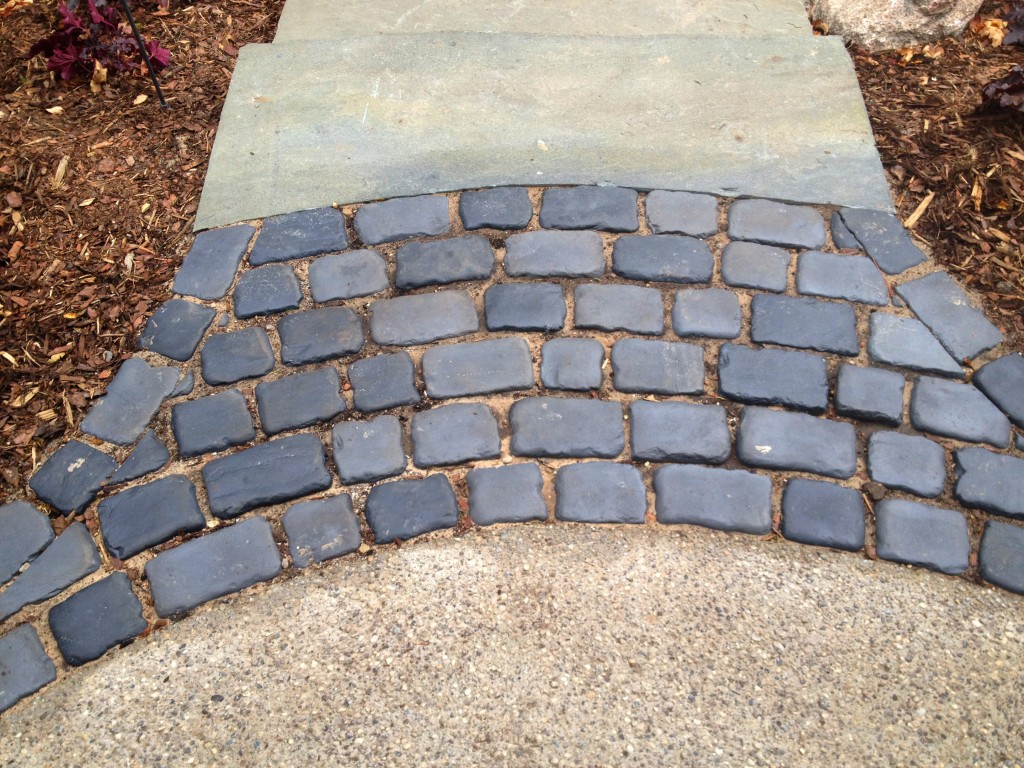 dark gray paver pathway between driveway and patio