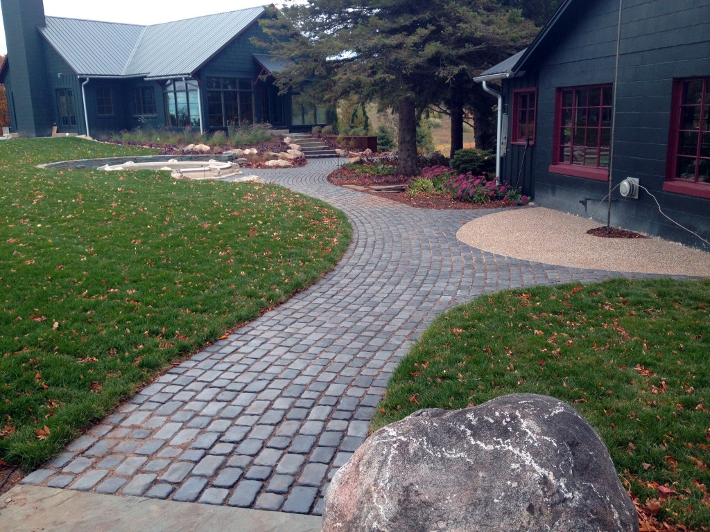 large rock in front of round grave paver sidewalk