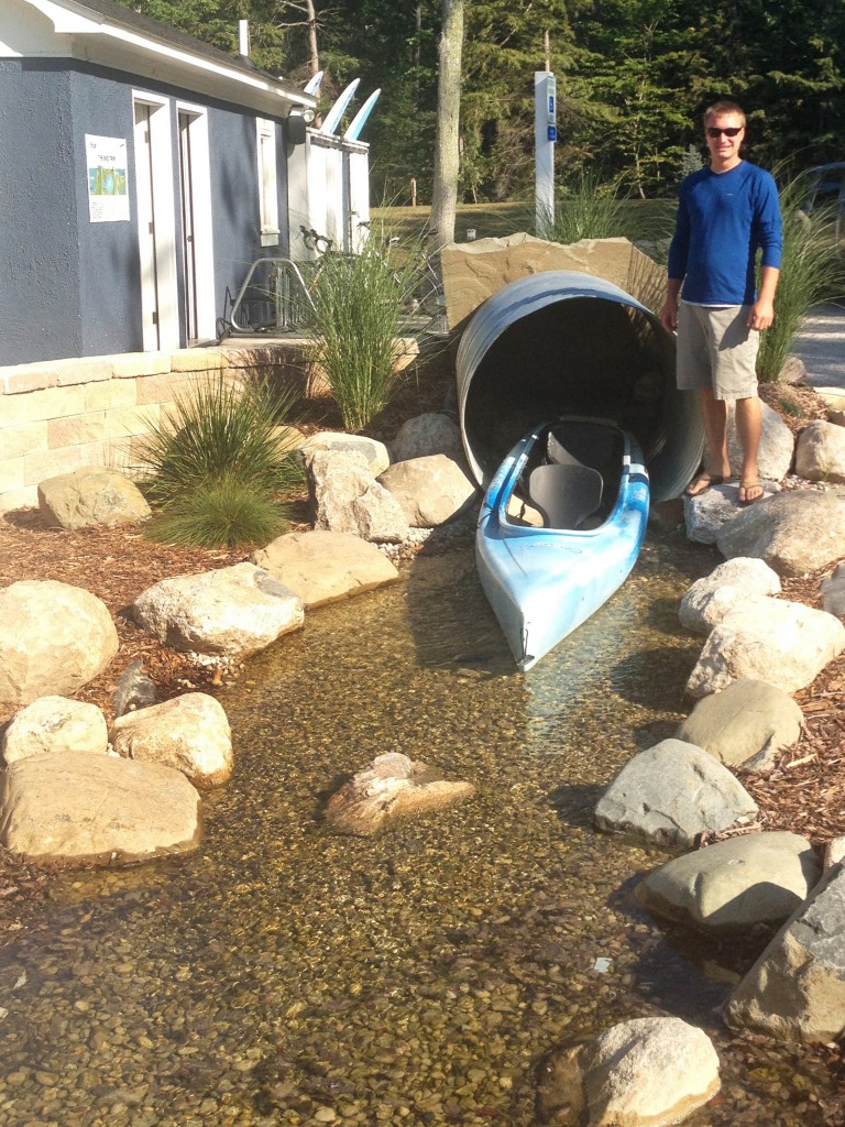 man standing next to blue kayak in creek