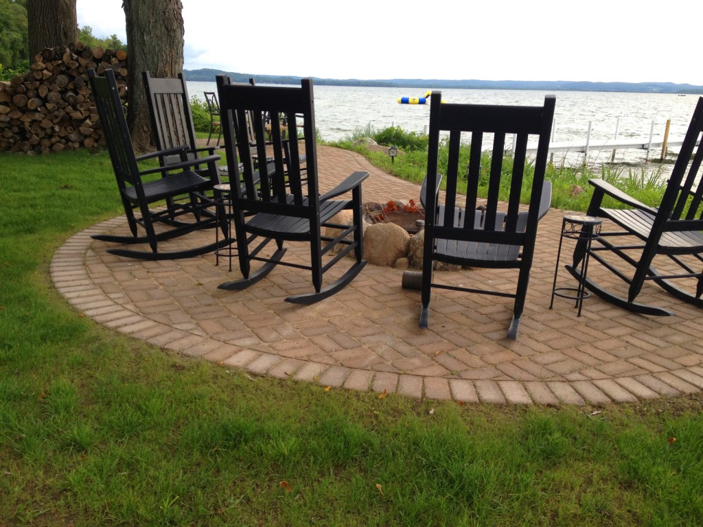 five black rocking chairs on a brick patio