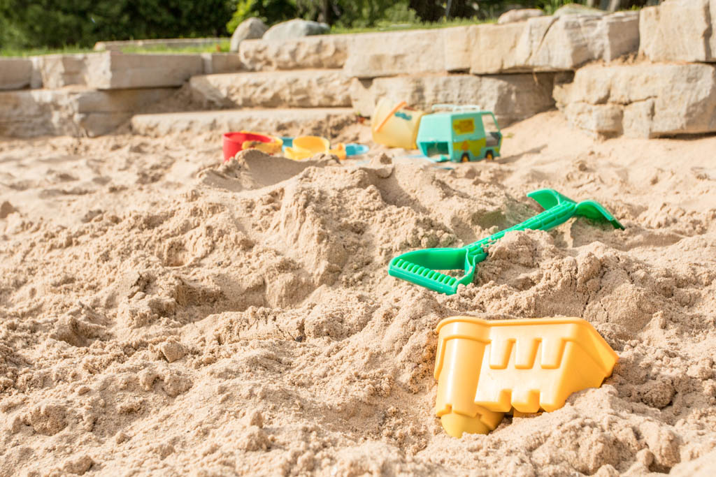 yellow plastic sand castle mold laying in sandbox