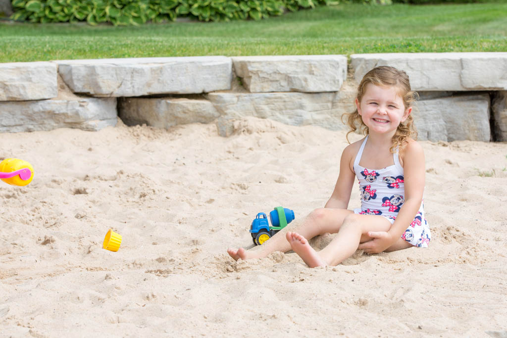 woman oversees children playing in the sandbox