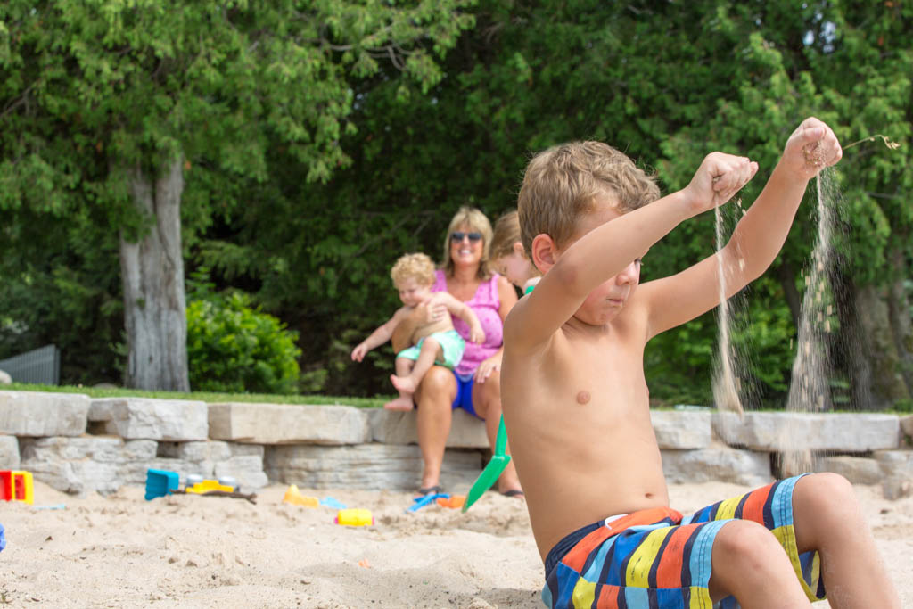 boy lets sand fall from his raised hands