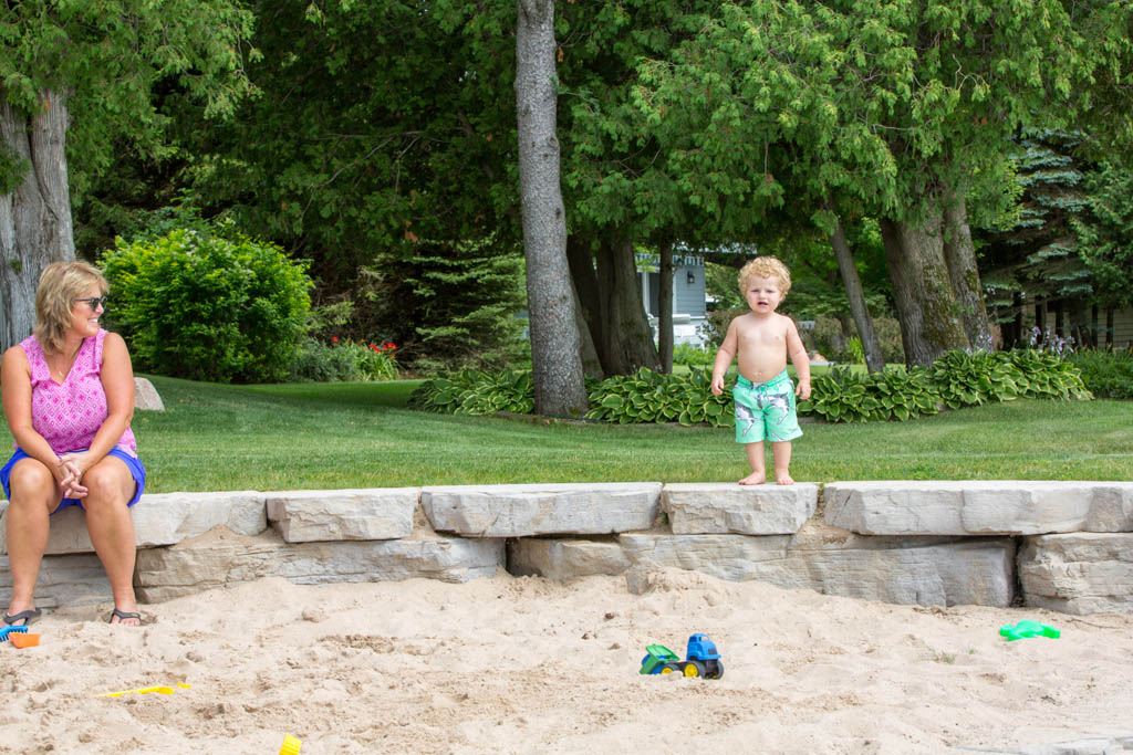 little boy walks around the sandbox walls