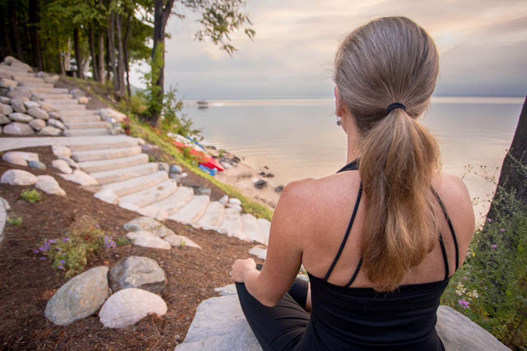 woman sitting cross legged overlooking the bay at sunrise