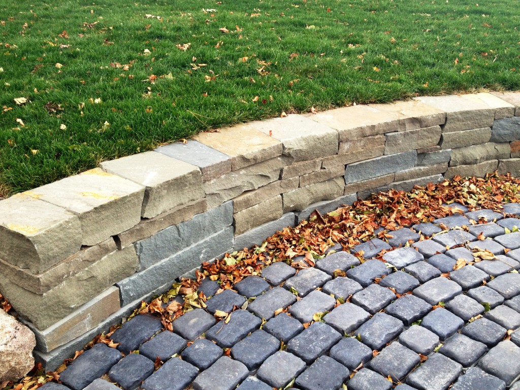 roughly hewn stone wall abutted agains round pavers