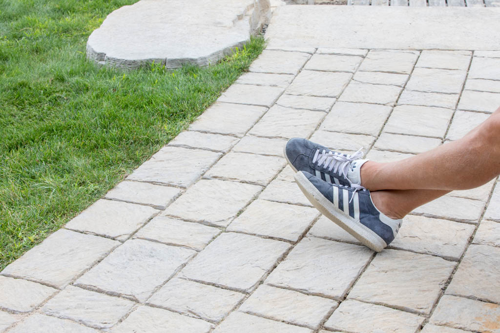 man's legs crossed resting on path way