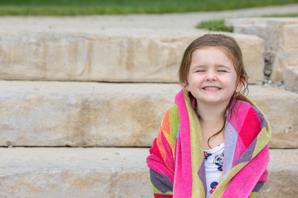 little girl grinning while drying off with towl